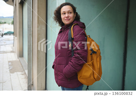 Woman With Burgundy Jacket And Orange Backpack Standing On City Street 136100832