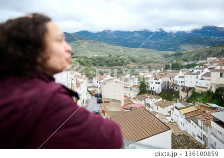Blurred Woman Overlooking A Hilly Village With Mountain Range In The Distance Blurred Woman Overlooking A Hilly Village With Mountain Range In The Distance 136100859