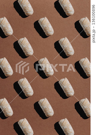 Seamless pattern of powdered sugar pastry rolls on brown background 136100896