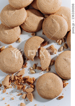 Broken peanut macarons with crumbs and nuts on white background, close up 136100898