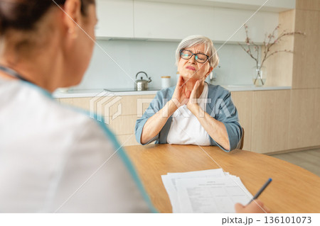Female doctor examining older senior woman in doctor office or at home. Old woman lady patient and doctor have consultation in hospital room. Medicine healthcare medical checkup. Visit to doctor 136101073