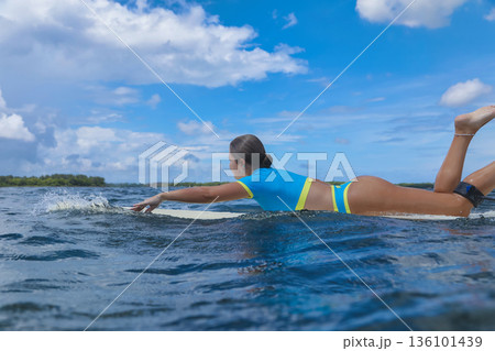 Athletic female surfer Amidst Scattered Clouds From Ocean Perspective Athletic female surfer Amidst Scattered Clouds From Ocean Perspective 136101439