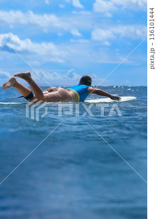 Calm Seaside Relaxation, Serene Woman Lounging On Surfboard Amidst Gentle Waves 136101444