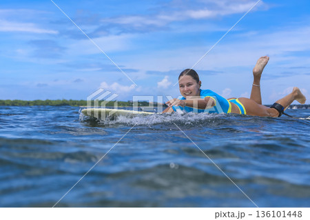 Portrait of female Surfer Paddling With Concentration And Strength 136101448