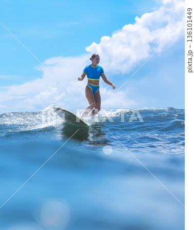 Contented Woman Surfing On Her Longboard Under Golden Sunlight In Ocean Contented Woman Surfing On Her Longboard Under Golden Sunlight In Ocean 136101449