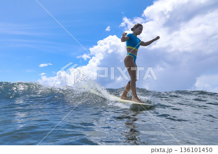 Woman Standing Proudly On Surfboard Amidst Turbulent Cloudy Backdrop 136101450