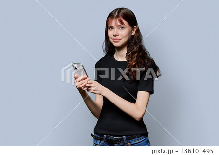 Portrait of female high school student with smartphone on gray background 136101495
