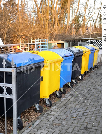 Multicolored plastic waste sorting containers lined up in a yard Multicolored plastic waste sorting containers lined up in a yard 136102145