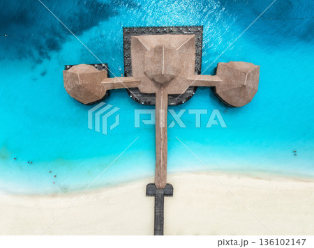 Aerial top down view of sea and wooden pier with thatched roof 136102147