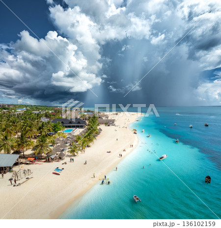 Aerial view of tropical sandy beach, blue sea and rain clouds Aerial view of tropical sandy beach, blue sea and rain clouds 136102159