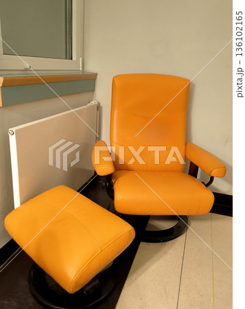 A bright orange leather chair with a footrest in the interior A bright orange leather chair with a footrest in the interior 136102165