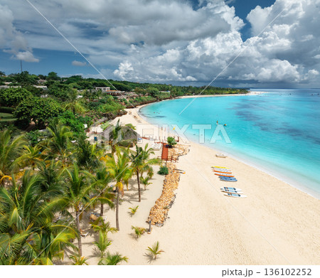 Aerial view of sandy beach, palm trees, umbrellas, boats, sea 136102252