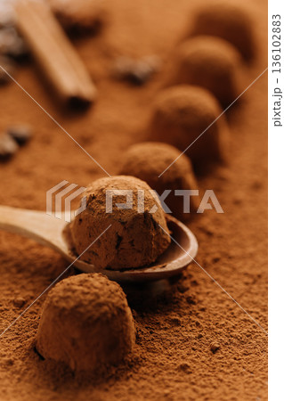 Cocoa truffles on wooden spoon in cocoa powder, closeup 136102883