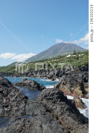 Volcanic coastline at Zona Balnear Ponta do Admoiro on Pico Island with black basalt rocks, turquoise Atlantic water, and Mount Pico Volcanic coastline at Zona Balnear Ponta do Admoiro on Pico Island with black basalt rocks, turquoise Atlantic water, and Mount Pico 136103214