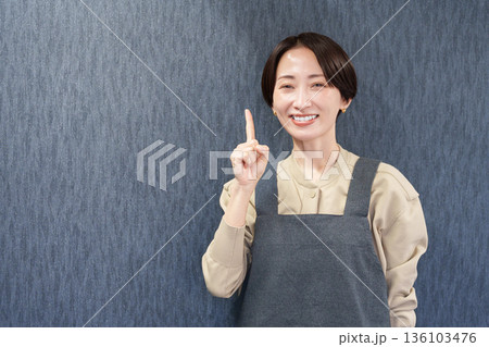 エプロンを着た指差す女性店員 136103476