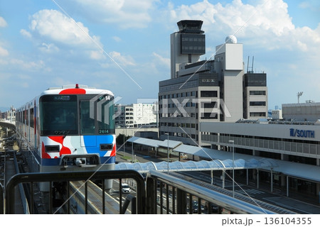 駅に入線してくる大阪モノレールの車両(斜め正面・関西万博ラッピング)と、大阪国際空港のターミナルビル 駅に入線してくる大阪モノレールの車両(斜め正面・関西万博ラッピング)と、大阪国際空港のターミナルビル 136104355