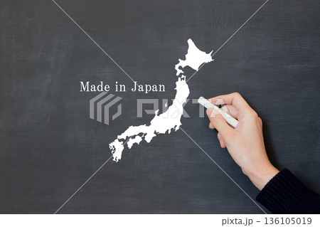 日本地図とメイドインジャパンの文字を黒板に描く人物の手 136105019