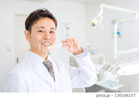 歯科医院と歯ブラシを持った医師 歯科医院と歯ブラシを持った医師 136106257