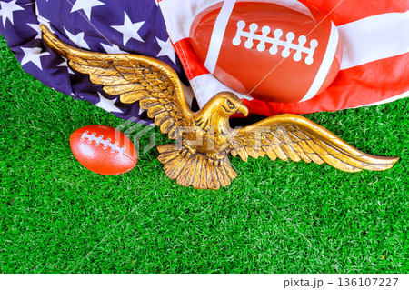 Eagle sculpture is placed with footballs an American flag of super bowl sports spirit event. 136107227