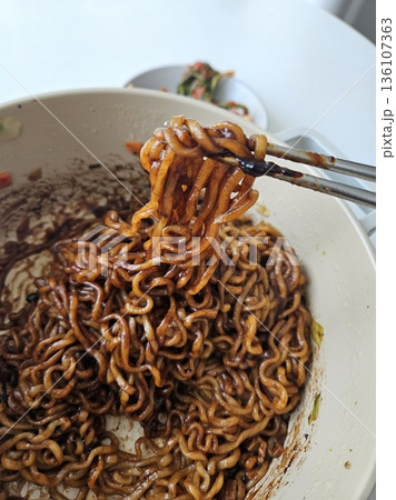 Savory jjapagetti noodles with a rich black bean sauce, topped with green onions and sesame seeds. A comforting Korean favorite that combines depth and flavor in each bite. 136107363