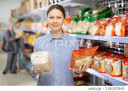 Woman in supermarket buys daily groceries, pasta Chinese noodles Woman in supermarket buys daily groceries, pasta Chinese noodles 136107645