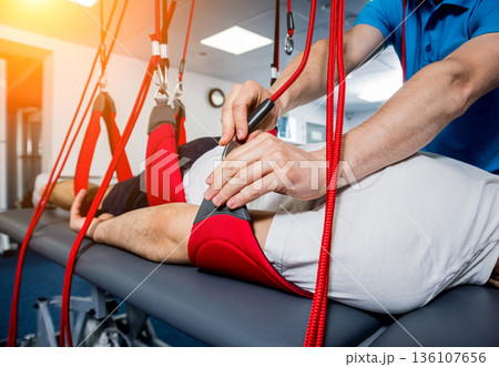 Physiotherapy. Suspension training therapy. Young man doing fitness traction 136107656