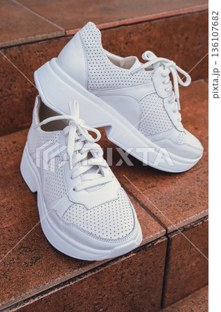 Fresh white leather sneakers without brand marks displayed. For design templates online shops and sustainability-themed marketing. Clean blank sneakers 136107682
