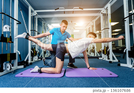 Rehabilitation therapy. Young man doing exercises on mat Rehabilitation therapy. Young man doing exercises on mat 136107686