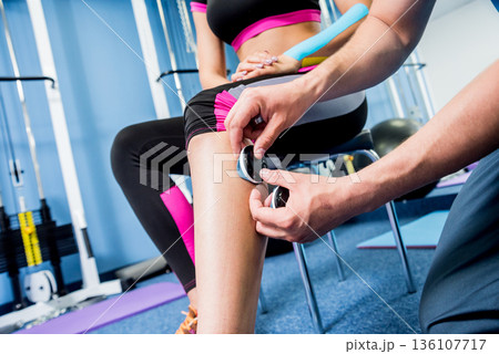 Physical therapist install electrostimulator on the muscles of the legs. Physical therapist install electrostimulator on the muscles of the legs. 136107717