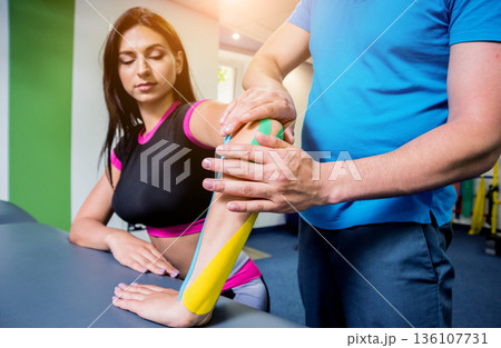 Kinesiotaping. Physical therapist applying tape to young beautiful womans spine 136107731