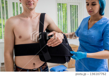 Nurse putting a sling on patients arm that is broken. Injury Nurse putting a sling on patients arm that is broken. Injury 136107762