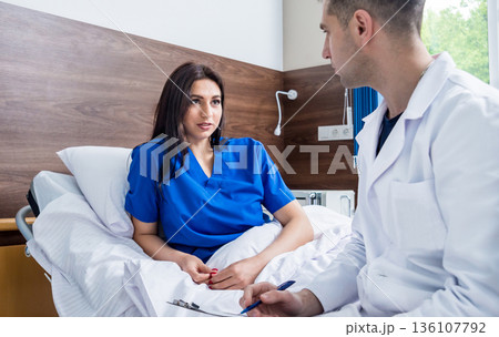 Traumatologist talking with young female patient in modern hospital 136107792