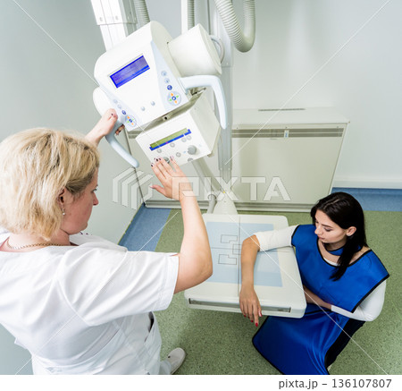 Radiologist and patient in a x-ray room. X-ray of human hand. 136107807