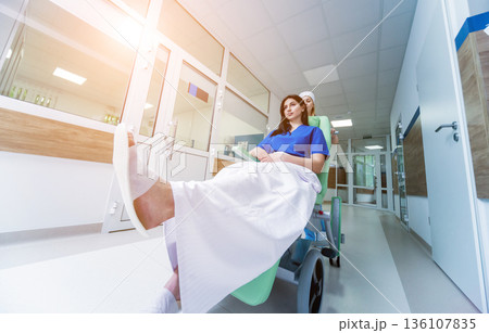 Nurse moves mobile medical chair with patient at hospital. Medical equipment. Nurse moves mobile medical chair with patient at hospital. Medical equipment. 136107835