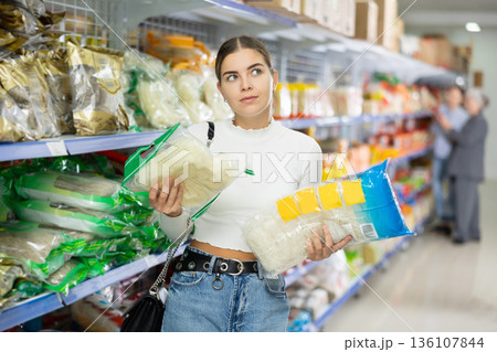 Young woman in supermarket buys daily groceries, pasta Chinese noodles 136107844