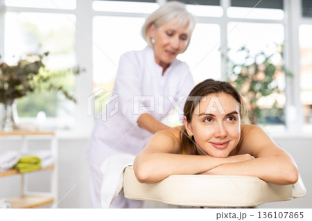 Young woman clinet satisfied with work of masseuse Young woman clinet satisfied with work of masseuse 136107865