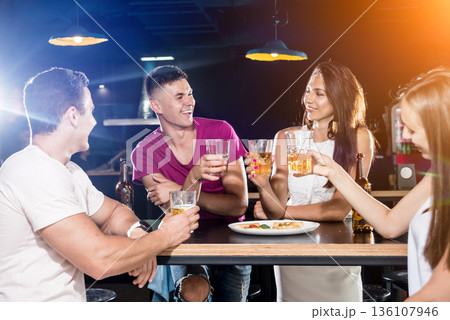 Cheerful friends in the pub. Drinking beer, talking, having fun. 136107946