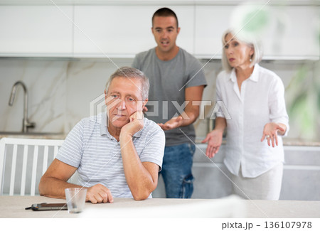 Elderly woman and adult man quarreling with elderly man in kitchen Elderly woman and adult man quarreling with elderly man in kitchen 136107978