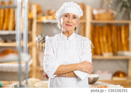 Portrait of professional mature female baker in white uniform in bakery Portrait of professional mature female baker in white uniform in bakery 136108291