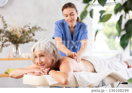 Young woman doing back massage to elderly woman 136108299