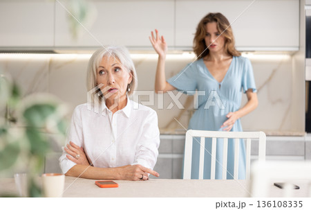 Quarrel of an mature mother and adult daughter at home. Adult daughter is unhappy with elderly mother Quarrel of an mature mother and adult daughter at home. Adult daughter is unhappy with elderly mother 136108335