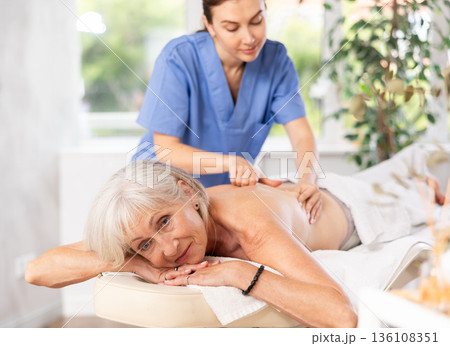 Elderly woman satisfied with work of masseuse Elderly woman satisfied with work of masseuse 136108351
