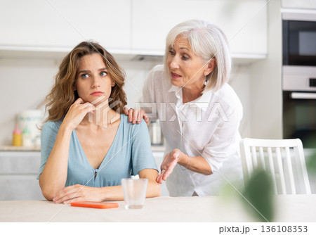Elderly mother asks for forgiveness from her adult daughter and calms her down after a domestic quarrel in kitchen Elderly mother asks for forgiveness from her adult daughter and calms her down after a domestic quarrel in kitchen 136108353