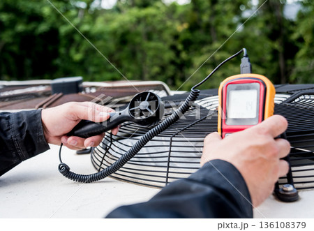 Technician use hand-held anemometer measuring air flowing measurement Technician use hand-held anemometer measuring air flowing measurement 136108379