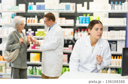Girl pharmacist in pharmacy works with computer Girl pharmacist in pharmacy works with computer 136108388