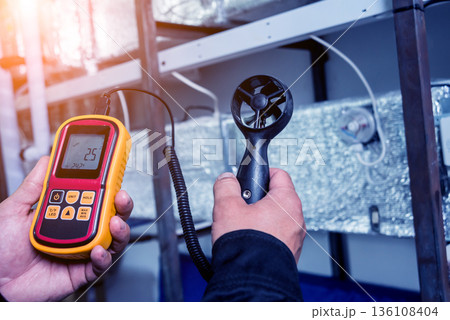 Technician use hand-held anemometer measuring air flowing measurement Technician use hand-held anemometer measuring air flowing measurement 136108404