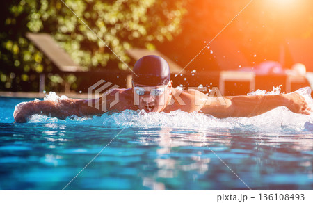 Young athletic man swimming in the swimming pool 136108493