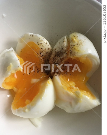 Boiled egg with smooth white exterior and firm yellow yolk inside, showcasing its simple appearance and versatile use as a nutritious and classic food item 136108652