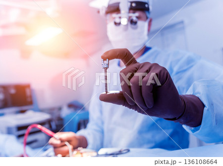 Spinal surgery. Surgeon show polyaxial screw in operating room Spinal surgery. Surgeon show polyaxial screw in operating room 136108664