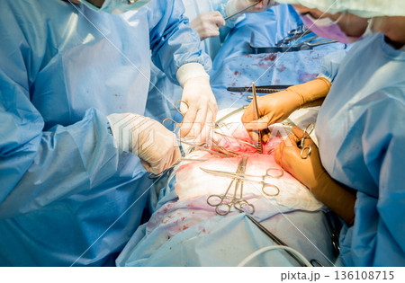 Surgeon and assistants in operating room with surgery equipment. 136108715